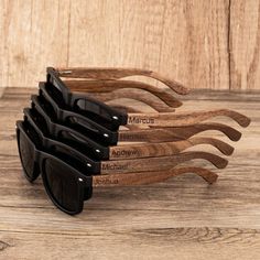 six wooden sunglasses with black frames on top of each other, sitting on a table