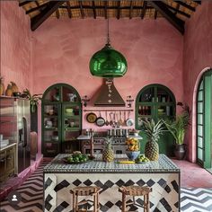 a kitchen with pink walls and black and white tile flooring, two stools in front of the island