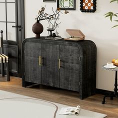 a black cabinet in a living room next to a wall with pictures and plants on it