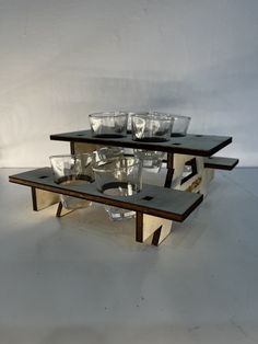 three tiered table with glass bowls on top and one shelf holding several empty glasses