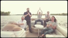 four people are sitting on a boat in the water and posing for a photo with their arms up