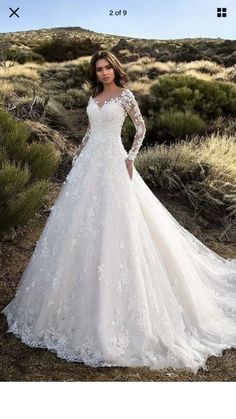 a woman in a white wedding dress standing on a dirt road with her hands on her hips