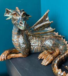 a statue of a dragon sitting on top of a black table next to a blue wall