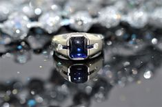 20K white gold designer ring set with an 8 x 6mm rectangular sugarloaf cabochon sapphire, 2 French cut sapphire baguettes, and 2 round diamonds having a total weight of 0.07 carats The inside of the shank is marked 1914 Rectangular Sapphire Ring With Accent Stones, Formal Square Cut Sapphire Ring, Modern Cabochon Sapphire Ring For Anniversary, Rectangular Sapphire Ring In White Gold, Rectangular Sapphire Ring With Accent Stones For Formal Occasions, Formal Rectangular Sapphire Ring With Accent Stones, Modern Sapphire Ring With Rectangular Shape, Sapphire Ring With Rectangular Stone For Formal Occasions, Rectangular Sapphire Ring For Formal Occasions