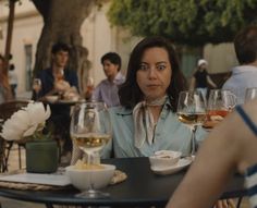 a woman sitting at a table with wine glasses in front of her