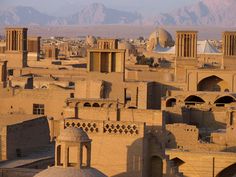 an old city in the middle of desert with mountains in the backgrouds