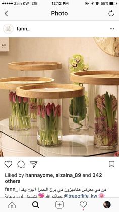 some flowers in vases sitting on top of a glass table next to a mirror