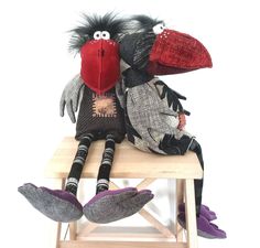 two stuffed birds sitting on top of a wooden table next to each other and one is wearing a red hat