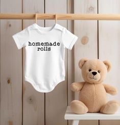 This adorable baby bodysuit is a perfect blend of comfort and charm, ideal for fall and holiday festivities. Made from soft, breathable cotton, it features a simple yet stylish design with the words "Handmade Rolls" in sleek black font. The black heat transfer vinyl (HTV) adds a touch of modern flair, making it versatile for any occasion. Whether dressing up for a family gathering or a cozy day at home, this bodysuit ensures your little one looks cute and feels comfortable. A delightful choice f Fall Cotton Bodysuit For Loungewear, Cotton Bodysuit For Fall Loungewear, Fall Cotton Loungewear Bodysuit, White Cotton Bodysuit For Loungewear, Cotton Onesie For Playtime In Fall, Fall Cotton Onesie With Letter Print, White Cotton Onesie For Fall, Cotton Basic Onesie For Playtime, Cotton Bodysuit With Letter Print For Playtime