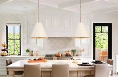 a large kitchen with white cabinets and an island in the middle, along with two pendant lights hanging from the ceiling