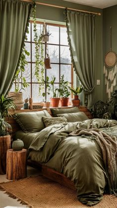 a bed with green sheets and pillows in front of a window filled with potted plants