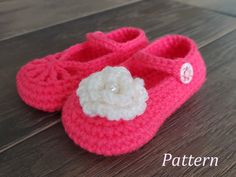 a pair of pink crocheted baby shoes with a white flower on the front