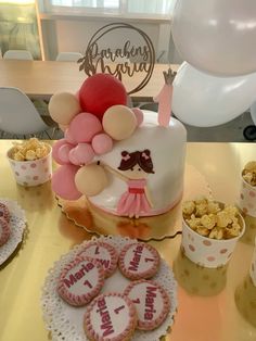 a birthday cake with balloons, cookies and popcorn on the table in front of it