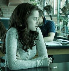 a woman sitting at a table in front of a laptop computer with her arms crossed