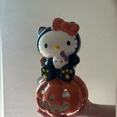 a hello kitty figurine sitting on top of a jack - o - lantern