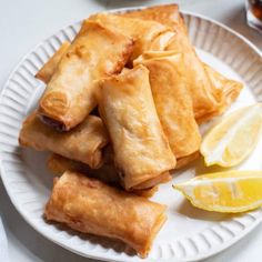 some food is on a white plate with lemon wedges