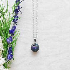 This necklace is made from a geode orb that has been plated with rainbow titanium. The surface of the stone shines with green, blue, purple and yellow colors. Some of the orbs have a geode druzy on one of the sides. The stone hangs from a silver plated chain. You can choose the length of the necklace you prefer. You will get a necklace at random. Please note that all necklaces are handmade and may differ from the pictured. The picture shows multiple necklaces. You will receive one necklace with Iridescent Sterling Silver Round Pendant Necklace, Iridescent Sterling Silver Necklace With Round Pendant, Iridescent Round Necklace For Gifts, Iridescent Round Necklace For Gift, Iridescent Necklace With Adjustable Chain For Gift, Iridescent Teardrop Pendant Necklace For Gift, Iridescent Round Pendant Necklace For Gift, Iridescent Pendant Necklace With Natural Stones, Gift Iridescent Crystal Necklace With Round Beads