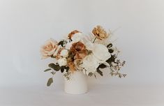 a white vase filled with lots of flowers