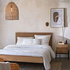 a bed with white sheets and pillows in a room next to a lamp on the wall