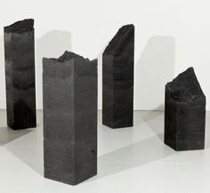 four pieces of black rock sitting on top of a white floor next to each other