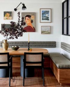 a wooden table sitting under a window next to a wall filled with pictures and plants