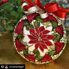 a christmas ornament with a red ribbon hanging from it's side on a table