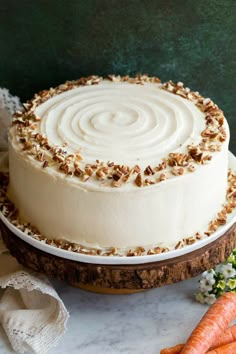 a cake sitting on top of a white plate covered in frosting and pecans