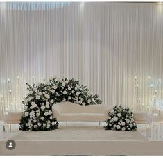 a wedding ceremony setup with white flowers and greenery in front of a curtained backdrop