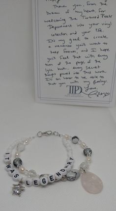 two bracelets with charms and a note on the table next to it is a handwritten letter