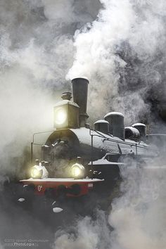 a steam engine train traveling through the fog