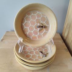 three yellow bowls stacked on top of each other with the lids open and bees in them