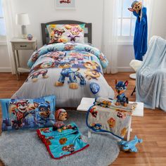 this is a bed with paw patrol comforters and toys on the floor next to it