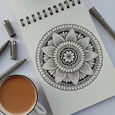 a cup of coffee sitting on top of a table next to a notebook and pen