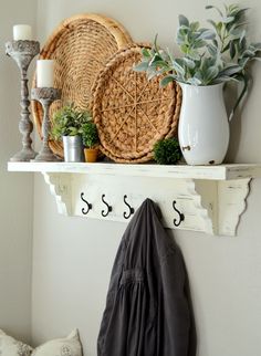 a shelf with some plants and other items on it next to a coat hanger