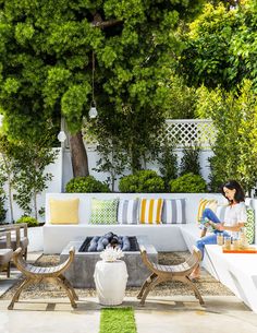 a woman sitting on a white couch in the middle of a patio with lots of furniture