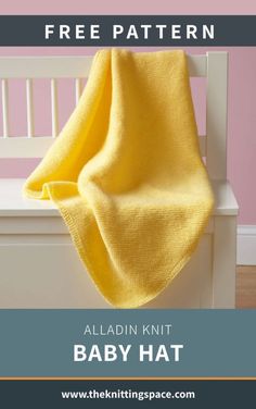 a knitted baby blanket sitting on top of a white bench next to a pink wall