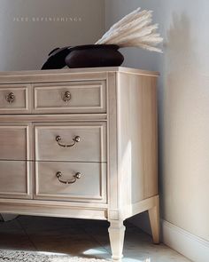 a white dresser with two drawers and a hat on top