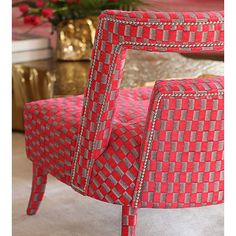 a red chair sitting on top of a floor next to a vase with flowers in it