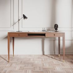 a wooden desk with a lamp on top of it next to a white wall and wood floor