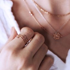 a close up of a person holding a necklace and wearing two rings on their fingers