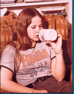 a woman sitting on a couch drinking from a cup