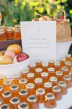 a table topped with lots of jars filled with honey and apples next to a basket of fruit