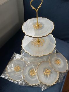 three tiered trays with gold flowers on them are sitting on a blue chair