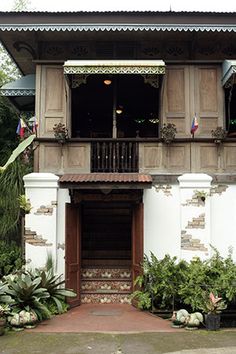 an old building with plants and potted plants on the front porch, next to it's entrance