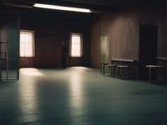 a person standing in an empty room next to some tables and chairs on the floor