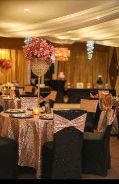 the tables are set up with black and gold linens, silver tablecloths, and pink flower centerpieces