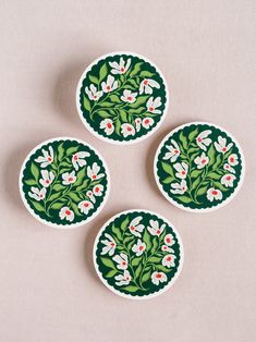 three green and white plates sitting on top of a table next to each other with flowers painted on them