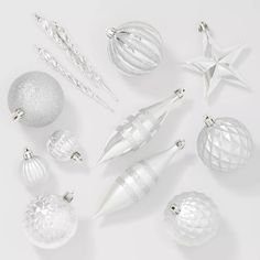 silver and white ornaments are arranged on a white surface