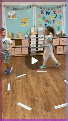 two young children are playing in a classroom with letters scattered on the floor and around them