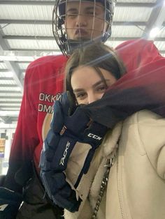 two people standing next to each other in front of a goalie helmet and net